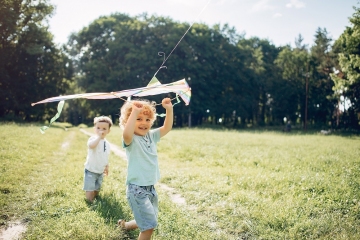 Little child in a summer field. Kids playing with a Kite