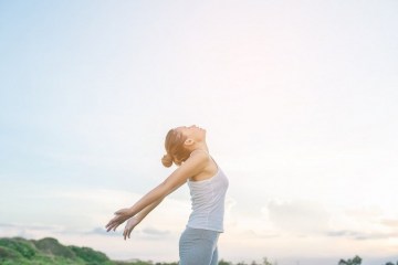 Young beautiful woman raising hands with beautiful view at meadow enjoy fresh air.